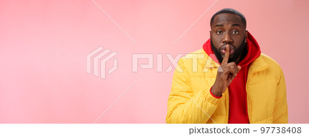 Waist-up serious-looking african-american bearded man in yellow jacket red hoodie bend camera asking keep quiet say shhh show shush gesture index finger on lips, confidential information taboo Waist-up serious-looking african-american bearded man in yellow jacket red hoodie bend camera asking keep quiet say shhh show shush gesture index finger on lips, confidential information taboo 97738408