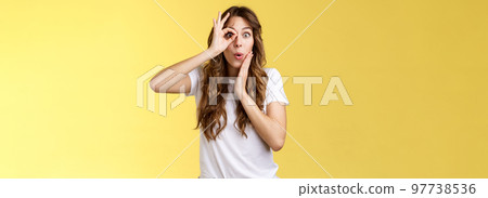 No way. Surprised impressed young funny attractive girl long chestnut hair fold lips admiration wow sound touch cheek astonished intrigued look through ok ring sign like monocle yellow background 97738536