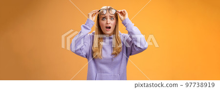 Shocked concerned young woman looking student ruin work staring disturbed upset take-off glasses popping eyes camera gasping speechless terrible acciddent happened, orange background Shocked concerned young woman looking student ruin work staring disturbed upset take-off glasses popping eyes camera gasping speechless terrible acciddent happened, orange background 97738919