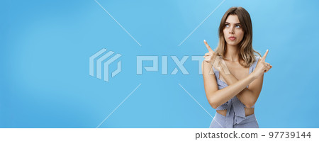Thoughtful questioned attractive female coworker trying make choice facing hard decision crossing hands against chest pointing left and right looking focused while thinking over blue background Thoughtful questioned attractive female coworker trying make choice facing hard decision crossing hands against chest pointing left and right looking focused while thinking over blue background 97739144