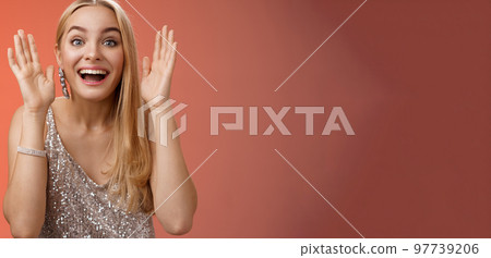 Impressed charming entertained blond european 25s woman in stylish silver glamour dress having fun playing peekaboo smiling joyfully hold palms near face laugh amused, standing red background Impressed charming entertained blond european 25s woman in stylish silver glamour dress having fun playing peekaboo smiling joyfully hold palms near face laugh amused, standing red background 97739206