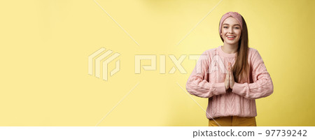 Please do me favour. Charming young female student wearing knitted sweater, headband pressing palms together in pray begging, asking for help smiling thankful, grateful for effort over yellow wall 97739242
