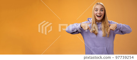 Excited fascinated european cute young girl blond hair smiling open mouth amused telling look down pointing downwards amazing cool new product recommend advertisement, orange background Excited fascinated european cute young girl blond hair smiling open mouth amused telling look down pointing downwards amazing cool new product recommend advertisement, orange background 97739254