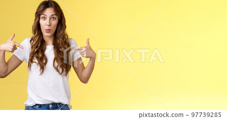 Wow just look. Impressed surprised cute wondered european girl pointing fingers center copy space white t-shirt folding lips amused astonished awesome promo great chance gaze you camera 97739285