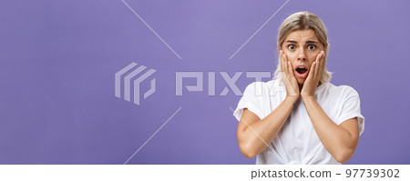 Shocked and worried silly european woman expressing empathy feeling sorry for poor animal in danger gasping opening mouth holding hands on face frowning feeling troubled over purple wall Shocked and worried silly european woman expressing empathy feeling sorry for poor animal in danger gasping opening mouth holding hands on face frowning feeling troubled over purple wall 97739302