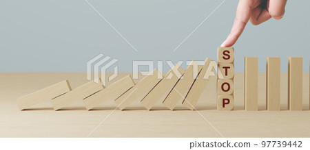 Hand stopping wooden domino business crisis effect or risk protection concept 97739442