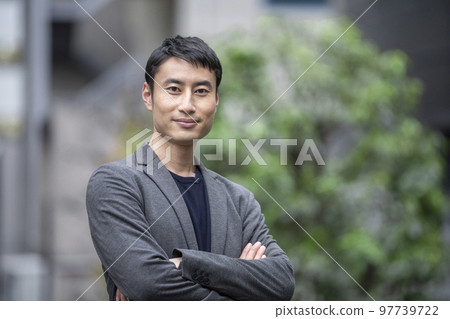 一位 30 多歲的微笑男子交叉雙臂看著相機的肖像 一位 30 多歲的微笑男子交叉雙臂看著相機的肖像 97739722