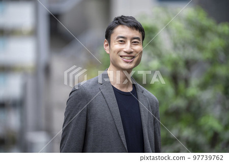 一個 30 多歲的男人對著鏡頭微笑的肖像 97739762