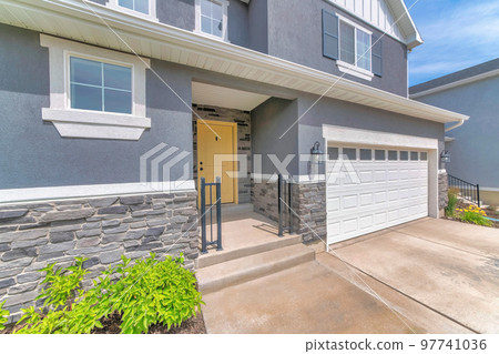 Exterior of a house with an attached garage and yellow front door Exterior of a house with an attached garage and yellow front door 97741036