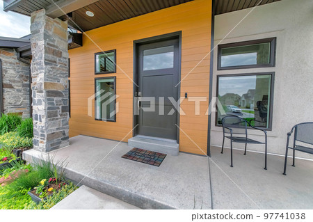 Entrance of a house with black front door and two arm chairs 97741038
