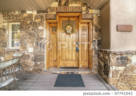 Wooden front door of a house with wreath, window and side panels 97741042
