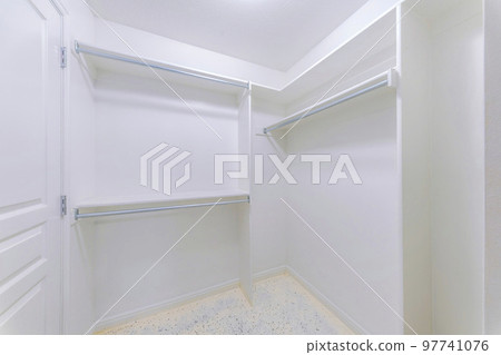 Small walk-in closet interior with white door and walls 97741076