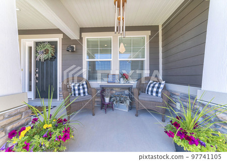 Nice front porch with potted flowers and two woven arm chairs Nice front porch with potted flowers and two woven arm chairs 97741105