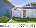 Wooden backyard gate with concrete arched entrance and stone veneer fence 97741151