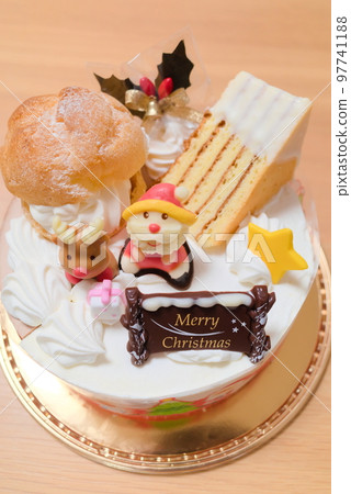 奢華的聖誕蛋糕,上面覆蓋著聖誕老人的糖果和奶油泡芙 奢華的聖誕蛋糕,上面覆蓋著聖誕老人的糖果和奶油泡芙 97741188