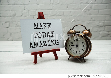 Make today amazing text and alarm clock on white brick wall and wooden background 97741650