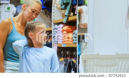 Beautiful mother and daughter choose looking for clothes in shopping mall. Mother and daughter shopper customer is looking and buying casual clothes in clothing store. Concept shopping clothes store. 97742652