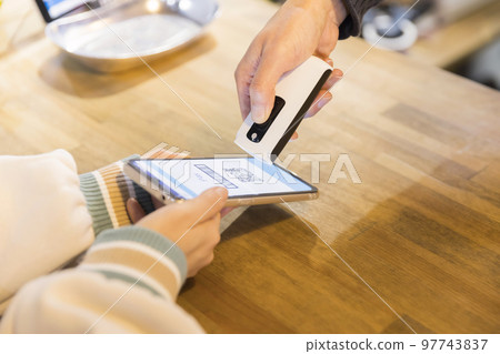 一個年輕女人的手在用智能手機付款 一個年輕女人的手在用智能手機付款 97743837