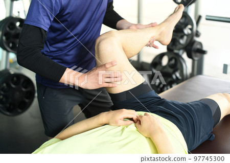 Male chiropractor and male patient doing sports massage 97745300