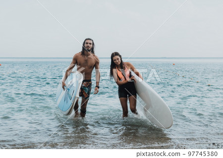 Sea woman and man on sup. Silhouette of happy young woman and man, surfing on SUP board, confident paddling through water surface. Idyllic sunset. Active lifestyle at sea or river. Sea woman and man on sup. Silhouette of happy young woman and man, surfing on SUP board, confident paddling through water surface. Idyllic sunset. Active lifestyle at sea or river. 97745380