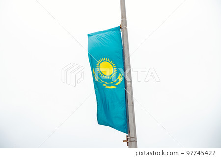 Turquoise yellow Kazakhstan flag on white cloudy sky background. Vertical flag of Kazakhstan on city street. Vertical flag of Kazakhstan on city street. 97745422