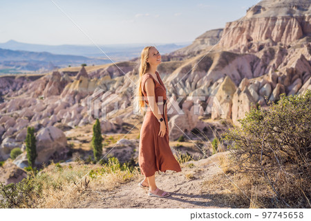 Young woman exploring valley with rock formations and fairy caves near Goreme in Cappadocia Turkey Young woman exploring valley with rock formations and fairy caves near Goreme in Cappadocia Turkey 97745658