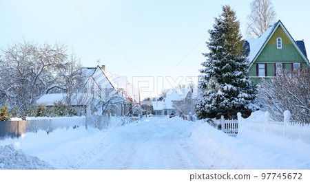 Winter fairy-tale landscape on the street with houses with a triangular roof and roads covered with a lot of snow 97745672