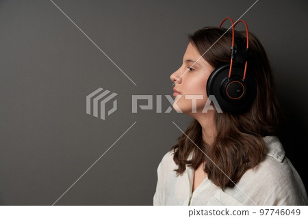 Closeup profile portrait of calm natural girl wearing headphones Closeup profile portrait of calm natural girl wearing headphones 97746049