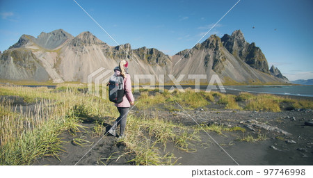 Morning scene of female traveler exploring Stokksnes cape with Vestrahorn on background Sunny summer day in Iceland 97746998