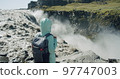 Woman standing at the cliff edge enjoying remote Detifoss waterfall in Iceland 97747003