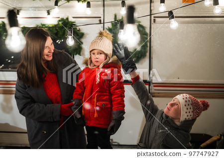 Caucasian woman and two with sons celebrate Christmas in a camper. The mother of two boys decorates the van with Christmas lights. 97747927