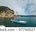 Young man in t-shirt and shorts floating on SUP board Young man in t-shirt and shorts floating on SUP board 97748027