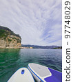 Close up of stand up SUP paddle board on lake or sea with blue water lilies, paddling in summer time at sunset. Summer family vacation Close up of stand up SUP paddle board on lake or sea with blue water lilies, paddling in summer time at sunset. Summer family vacation 97748029