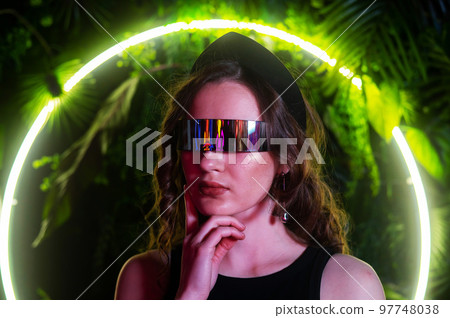 Caucasian woman in panoramic sunglasses against the background of an annular neon lamp in plants.  Caucasian woman in panoramic sunglasses against the background of an annular neon lamp in plants.  97748038