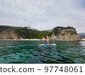 Fit woman in bikini relaxing on a sup surfboard, floating on the clear sea on cliff background Fit woman in bikini relaxing on a sup surfboard, floating on the clear sea on cliff background 97748061