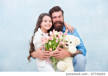father and daughter embrace with spring tulip flower bouquet and teddy bear toy, womens day 97748883