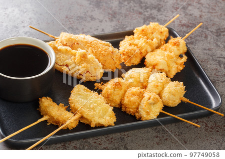 Kushikatsu or kushiage is a Japanese dish of deep-fried skewered meat and vegetables closeup on the plate. Horizontal Kushikatsu or kushiage is a Japanese dish of deep-fried skewered meat and vegetables closeup on the plate. Horizontal 97749058