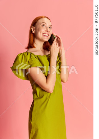 Portrait of young beautiful girl in cute dress talking on phone with happy face, posing over pink background 97750110