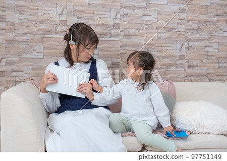 A mother who operates a tablet while raising a child A mother who operates a tablet while raising a child 97751149