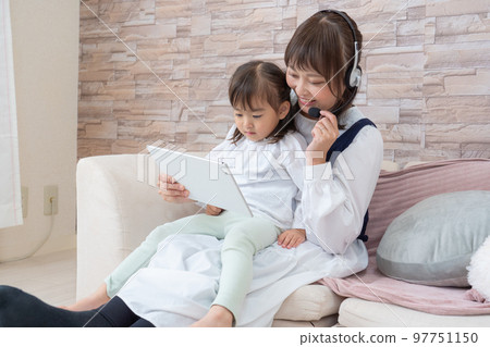 A mother who operates a tablet while raising a child A mother who operates a tablet while raising a child 97751150