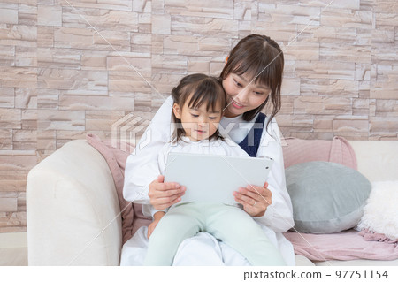 A mother who operates a tablet while raising a child 97751154