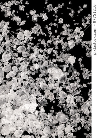 Sea salt, fleur de sel, close-up of crystals on a black surface. Also flor de sal, a salt that forms a thin, delicate crust on the sea water that evaporates. Finishing salt to flavor and garnish food. 97751216