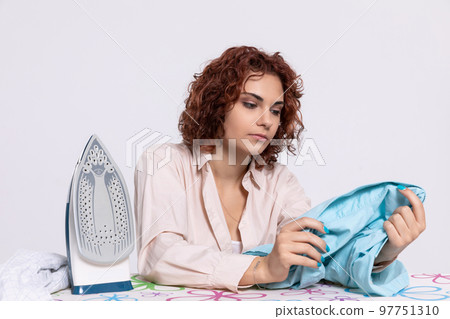 Before ironing, the girl carefully inspects the shirts. Before ironing, the girl carefully inspects the shirts. 97751310