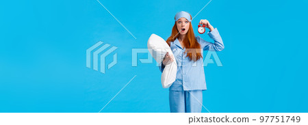 Vertical full-length shot shocked and startled cute redhead female in sleeping mask and pyjama, holding pillow and alarm clock, open mouth gasping worried, stare camera, blue background Vertical full-length shot shocked and startled cute redhead female in sleeping mask and pyjama, holding pillow and alarm clock, open mouth gasping worried, stare camera, blue background 97751749