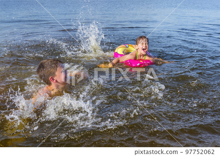 Happy children playing on the beach with splashing water. The concept of summer holidays 97752062