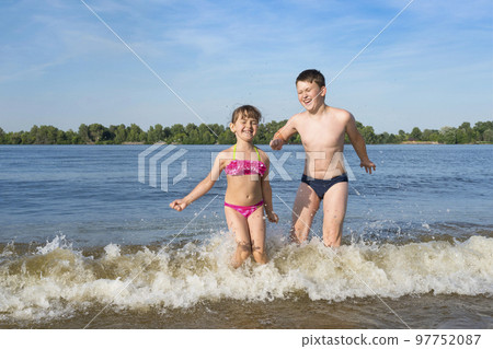 Happy children playing outdoors in the river. Beach season. The concept of a healthy lifestyle 97752087
