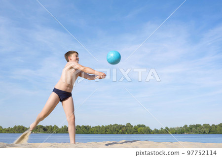 A teenager playing volleyball on the beach on a sunny day. Active lifestyle 97752114