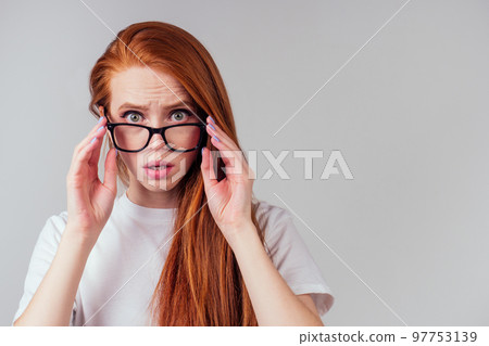 redhaired ginger woman wearing glasses and white cotton eco t-shirt in gray studio background redhaired ginger woman wearing glasses and white cotton eco t-shirt in gray studio background 97753139