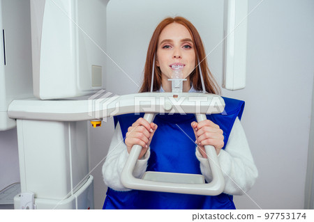 Close up head shot of redhaired ginger girl taking dental tac with cephalometric panorama xray machine in clinic Close up head shot of redhaired ginger girl taking dental tac with cephalometric panorama xray machine in clinic 97753174