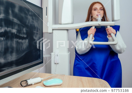 Close up head shot of redhaired ginger girl taking dental tac with cephalometric panorama xray machine in clinic 97753186